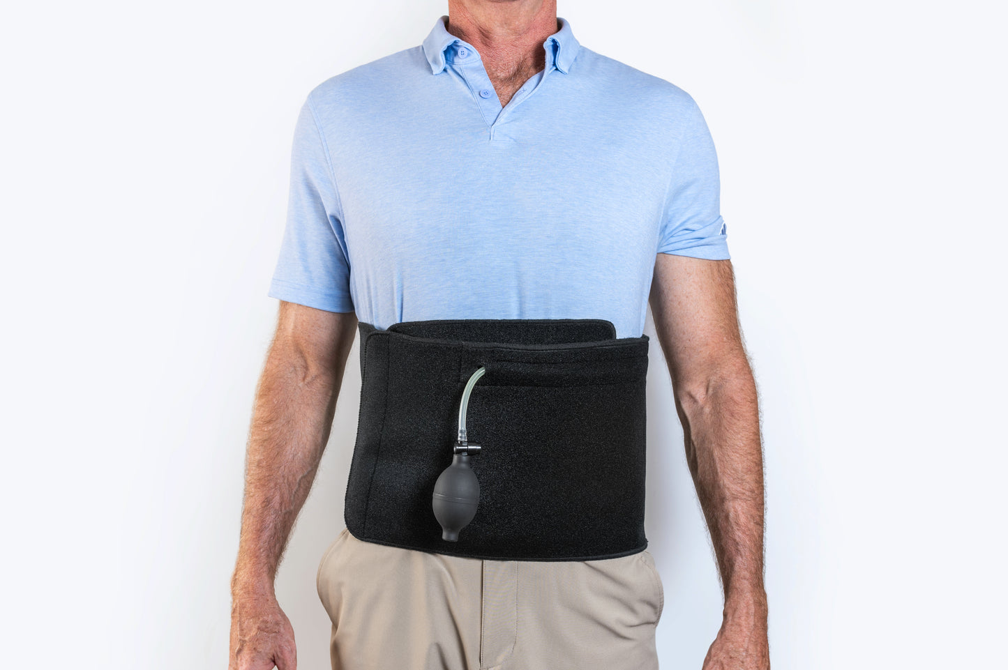 Man standing facing the camera wearing Back Fix, positioned between the hips and ribs for lumbar support. The front-facing pump is clearly visible, highlighting the adjustable inflation system for customized back support and posture correction.